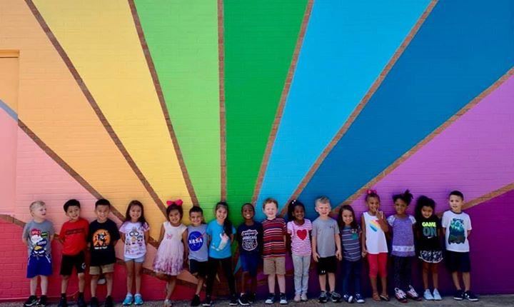 group of prekindergartners in front of rainbow wall